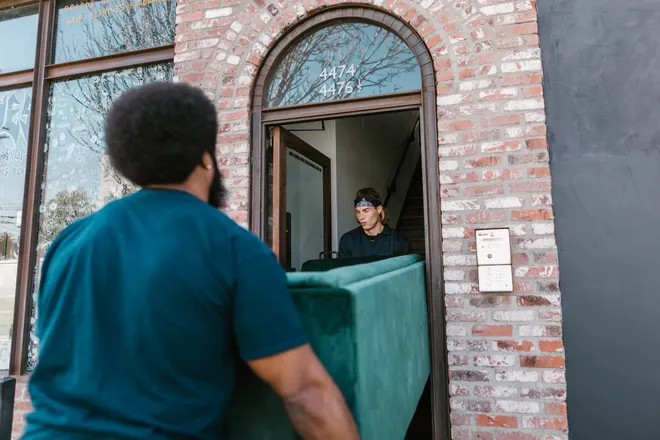 Two haulers carrying an old couch out through a doorway